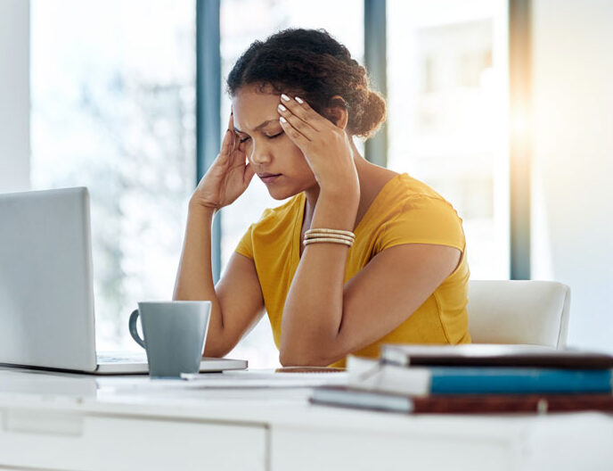Women feeling overwhelmed by anxiety while working on a laptop