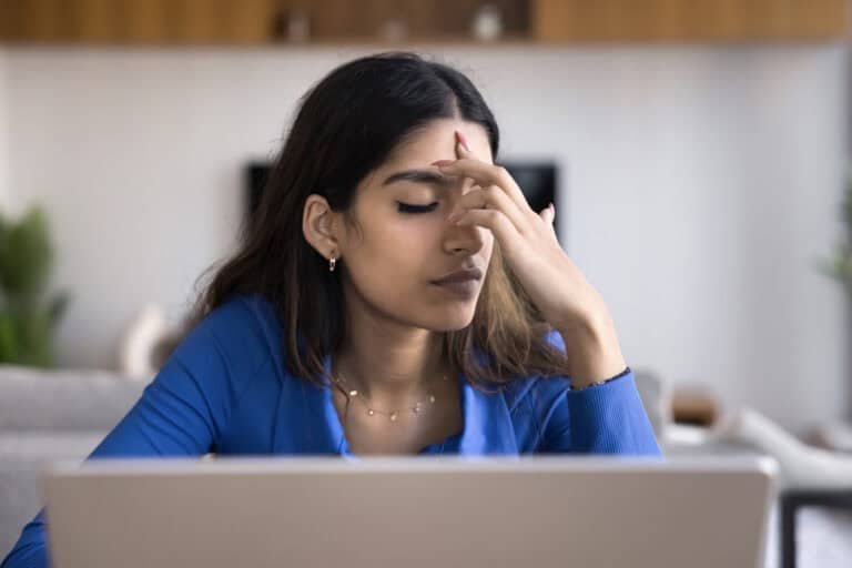 Woman experiencing decision fatigue and mental exhaustion while working on a laptop