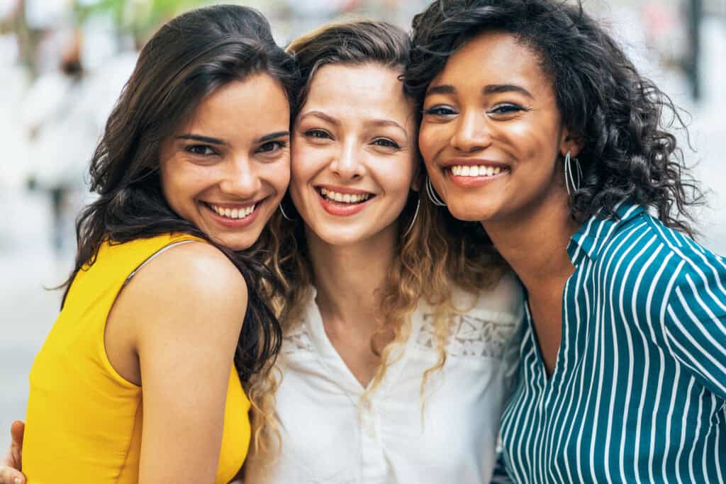 Three women smiling together, accompanying information about anxiety therapy for millennial women.